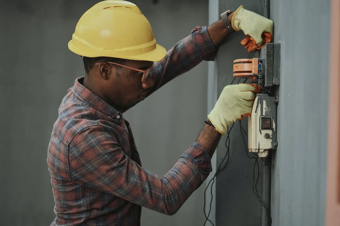 African American man installing electrical gear panne. 